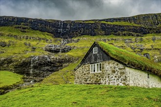 Grasstop roof house before a waterfall, Saksun, Streymoy, Faroe islands, Denmark, Europe