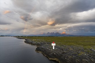 Small lighthouse at the coast, behind the mountain range Seven Sisters, light mood with rainbow,