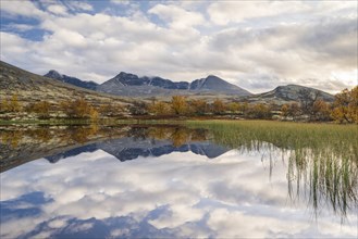 Reflection of the autumn landscape in Rondane National Park, mountains Hogronden, Midtronden and