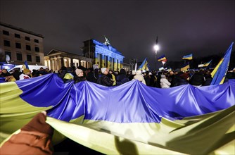 People demonstrate with a huge Ukrainian flag at the Brandenburg Gate on the anniversary of the