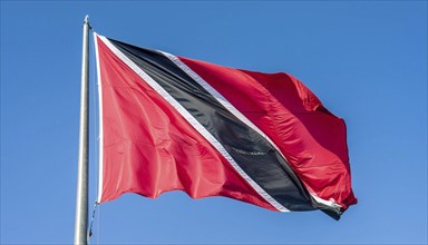 The flag of Tobago, Caribbean, flutters in the wind, isolated against a blue sky