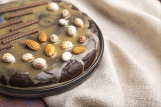 Homemade chocolate brownie cake with caramel cream and almonds with cup of coffee on a colored