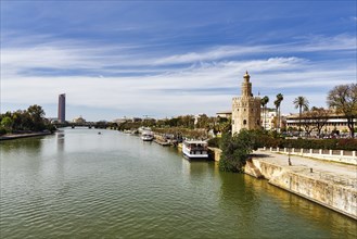 View over the Rio Guadalquivir with Torre del Oro and riverside promenade, Torre Sevilla in the