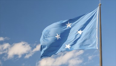 The flag of Micronesia, Pacific Islands, fluttering in the wind, isolated against a blue sky