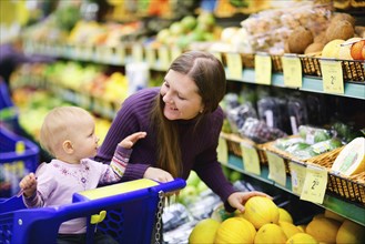 A young mother goes shopping with her baby in the supermarket, Scandinavia