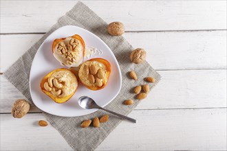 Persimmon dessert with curd, nuts and milk cream on white wooden background. top view, copy space