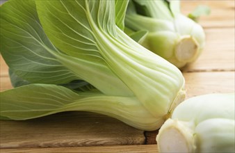 Fresh green bok choy or pac choi chinese cabbage on a brown wooden background. Side view, close up