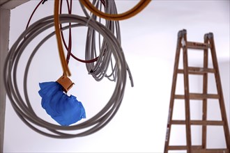 Cables hanging from a construction site on a wall, in the background is a ladder, Berlin, 03.07