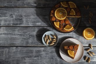 Orange cake on a gray wooden background. Hard light. contrast, low key. Top view, flat lay, copy