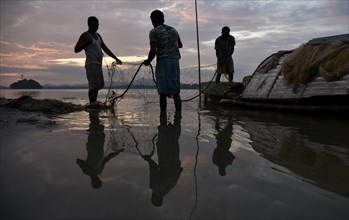 Fishermen cleaning their fishing nets after fish in the Brahmaputra river, in Guwahati, Assam,