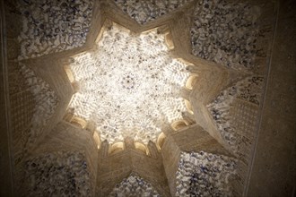 Illuminated view at night of richly decorated Islamic stonework ceiling Alhmabra palaces, Granada,