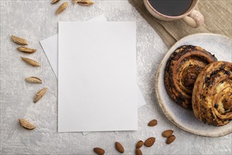 White paper invitation card, mockup with almonds, bun, cup of coffee, linen textile on gray