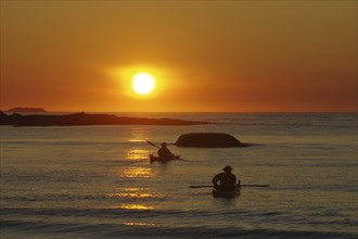 Two kayakers paddling out to sea in the midnight sun, Ramberg, Lofoten, Nordland, Norway, Europe