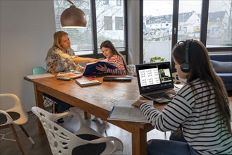 Homeschooling, during the lockdown in January 2021, mother helps her two daughters, at home,