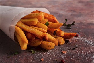 Gebratene Pommes frites, in einer Papiertüte, auf einem abstrakten Hintergrund, keine Menschen,