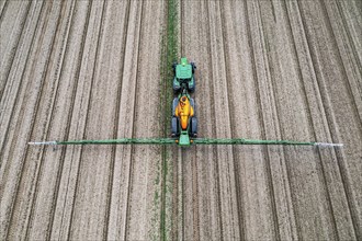 Farmer working a field, crop protection agent being sprayed, field with young sugar beet plants,