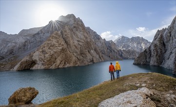 Couple at the blue mountain lake between rocky steep mountain peaks, Sun Star, Kol Suu Lake,