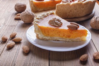 A slice of traditional american sweet pumpkin pie on brown wooden background. close up