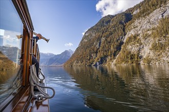 A trumpet is played on the echo wall of a tourist boat, Königssee, autumnal mountain landscape