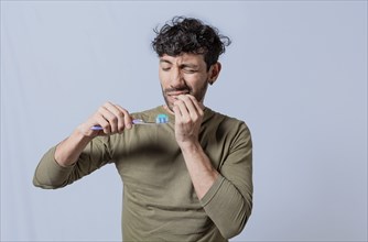 Person with gingivitis holding toothbrush. People holding toothbrush with gum pain. Man holding