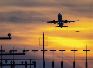 Runway lighting, approach aids, at Düsseldorf International Airport, sunset, aircraft taking off