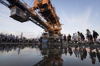 An open-cast mining excavator is reflected in a puddle at the Melt Festival in Ferropolis on 13