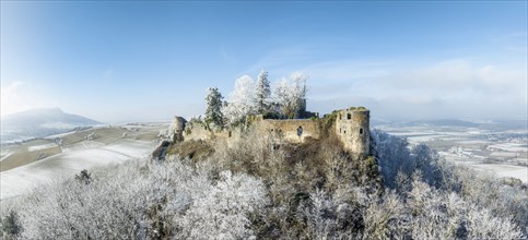 Aerial view of the snow-covered Hegau volcano MÃ¤gdeberg, with remains of a castle wall, surrounded