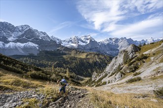 Mountaineers climbing up a hiking trail, mountain panorama with steep rocky peaks, yellow-coloured