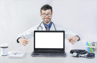 Handsome doctor pointing at an advertisement on the laptop screen. Smiling doctor pointing at an