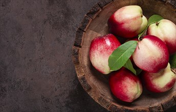 Ripe nectarine, in a wooden plate, brown background, top view, no people