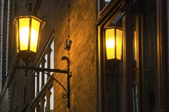 A shining lantern is reflected in a window pane of a house in Stralsund, 12/09/2016