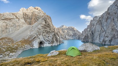 Green tent at the turquoise mountain lake Kol Suu with rocky steep mountains, Kol Suu Lake, Sary