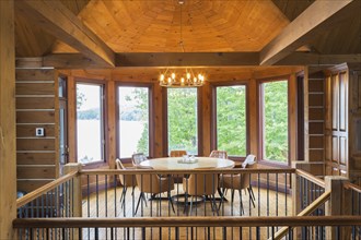 Staircase and round wooden dining table with tan leather armchairs in dining room inside a milled