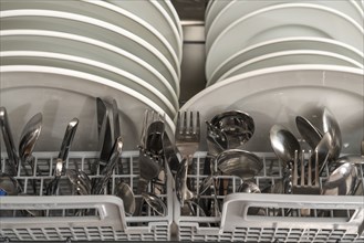 Dishwasher, full, with cleaned crockery, cutlery, cooking utensils