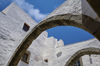 View upwards of arches and white walls against a blue sky, part of a historic monastery, Inside the