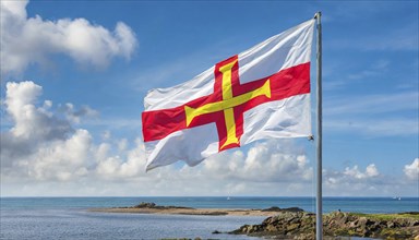 The flag of the Isle of Guernsey, Great Britain, flutters in the wind