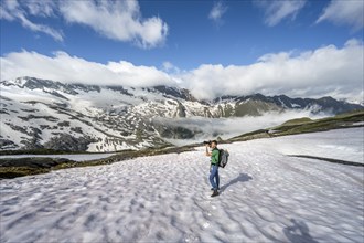 Mountaineer photographed on a snowfield, behind mountain panorama with high fog in the valley,