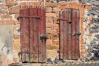 Weathered wooden doors to stable and loo, with heart, façade made of sandstone, natural stone,