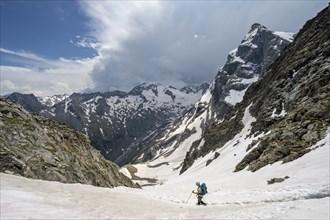 Female mountaineer hiking in a snowfield, Nördliche Mörchnerscharte, behind mountain peak Greizer