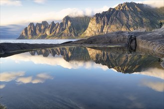 Reflections of clouds, rocks and the Devil's Tooth mountain in the evening sunlight, Tungeneset,