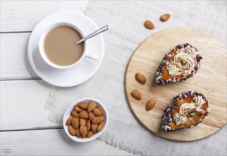 Cakes with chocolate chips and cream decorations on wooden board on white wooden background. with