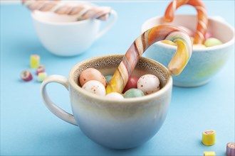 Heap of multicolored caramel candies in cups on blue pastel background. close up, side view,