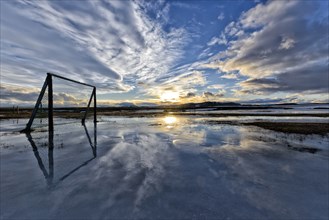 Sunset over clouds, football playground flooded with melting snow, winter, farm Mödrudalur located