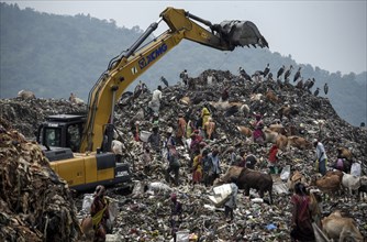 Municipality workers working with excavator as rag pickers searches for recyclable materials next