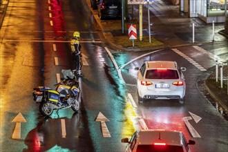 Policeman with motorbike, in rainy weather, blocking a road, police motorbike with blue light