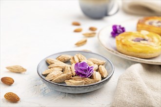 Small cheesecakes with jam and almonds with cup of coffee on a white concrete background and linen