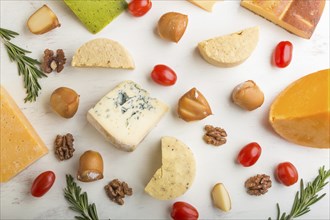 Set of different types of cheese with rosemary and tomatoes on a white wooden background. Top view,