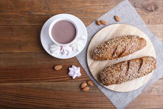 Rye bread with sunflower seeds, sesame and flax with cup of cocoa on brown wooden background. top