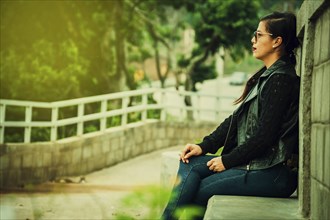 Relaxed girl sitting on a bench. attractive young woman with glasses sitting on a bench meditating