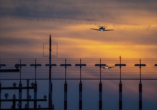 Runway lighting, approach aids, at Düsseldorf International Airport, sunset, aircraft taking off